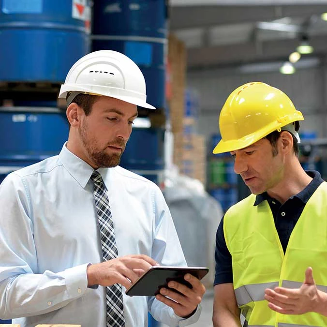 2 mannen met veiligheidshelmen bekijken tablet